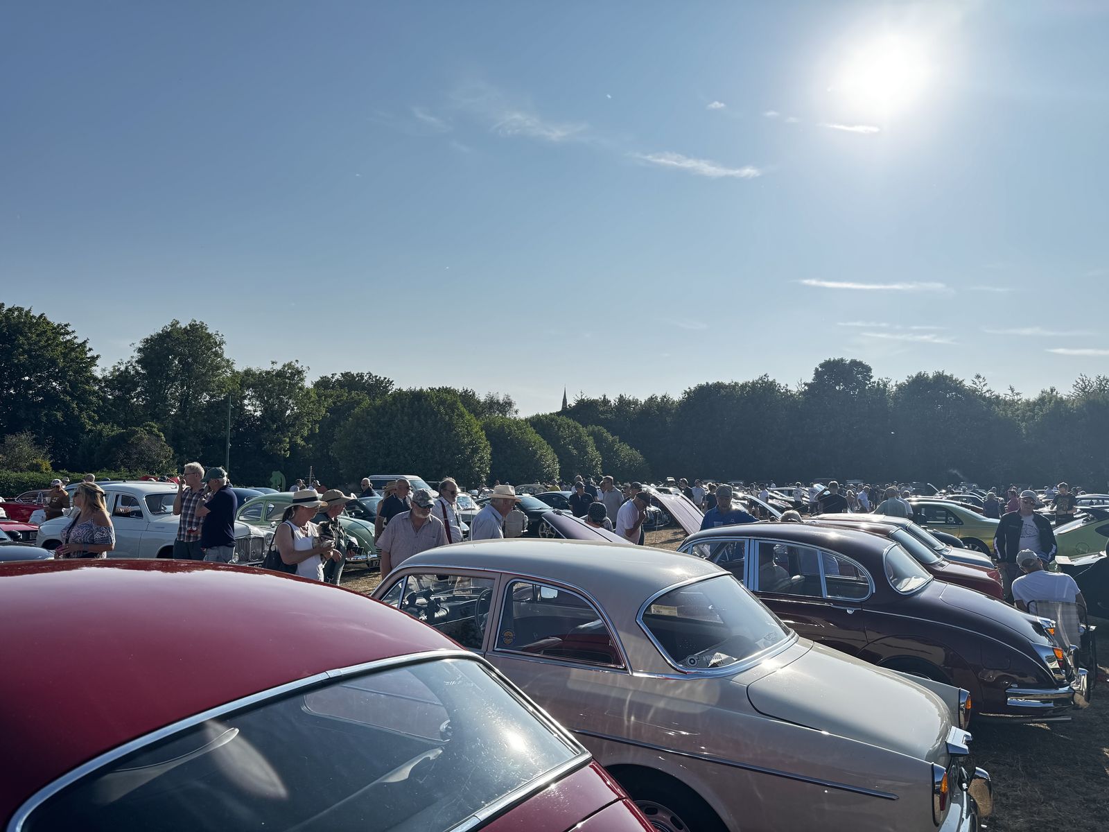 Rows of classic cars and visitors under a clear sky at the Greetham Car Show
