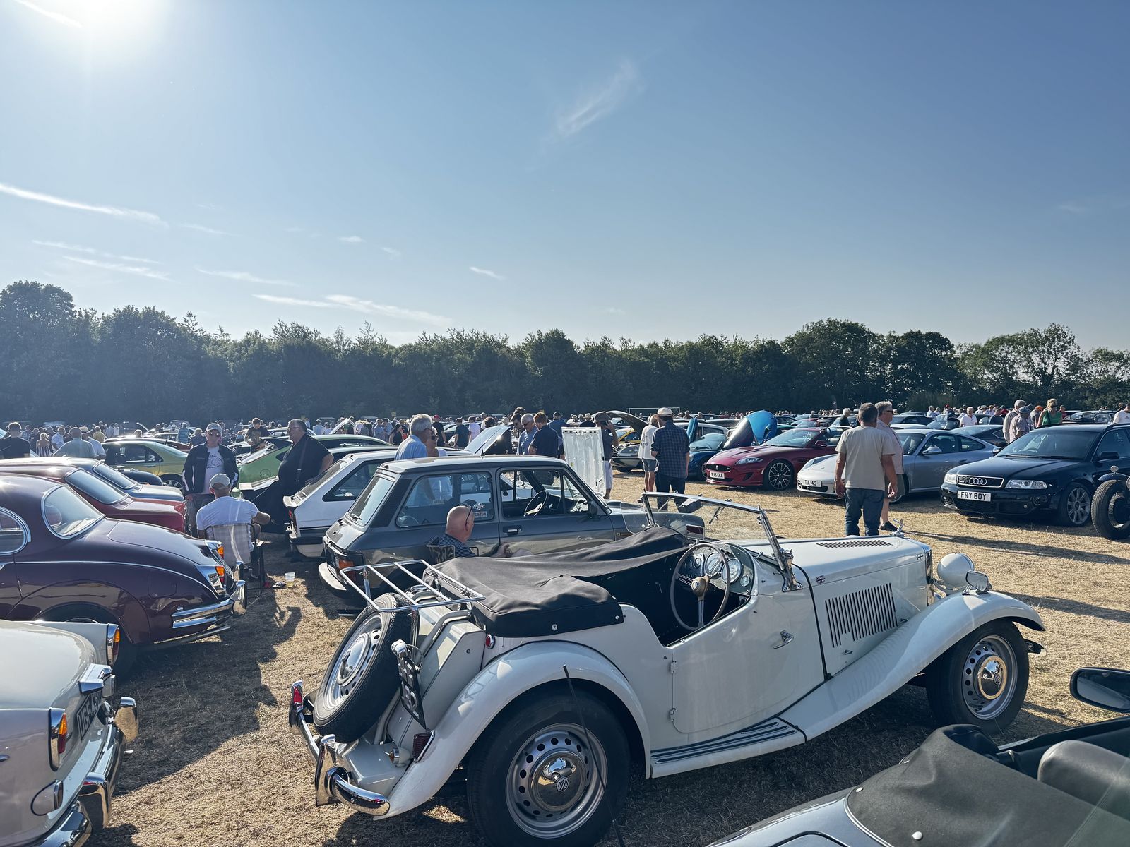 A vintage MG and other classics parked among a large crowd at the Greetham Car Show